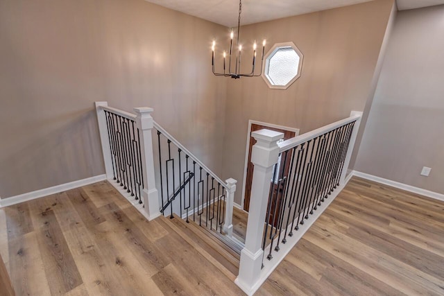 staircase featuring hardwood / wood-style flooring and a notable chandelier