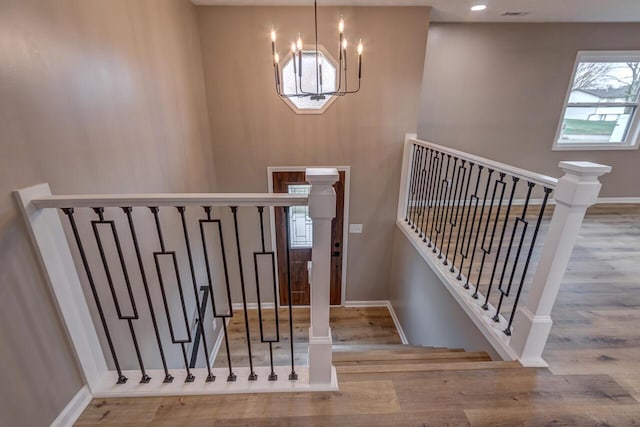 staircase featuring hardwood / wood-style flooring and an inviting chandelier