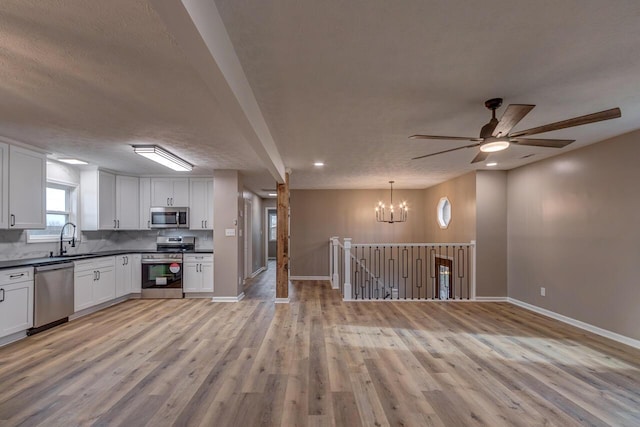 kitchen featuring appliances with stainless steel finishes, light wood-type flooring, a textured ceiling, sink, and white cabinetry