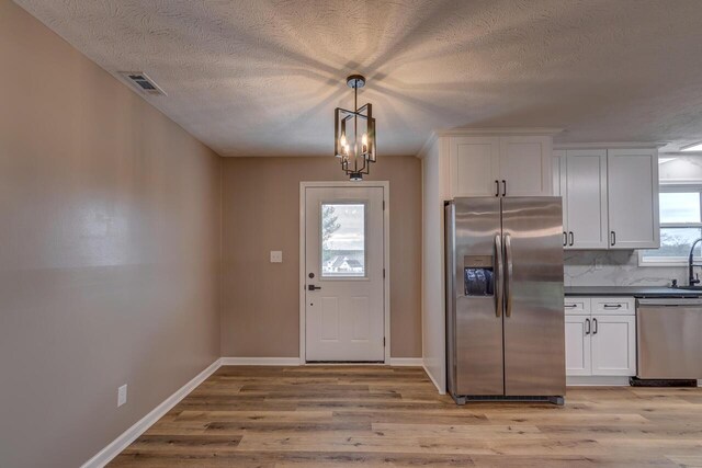 kitchen featuring white cabinets, plenty of natural light, light hardwood / wood-style floors, and appliances with stainless steel finishes