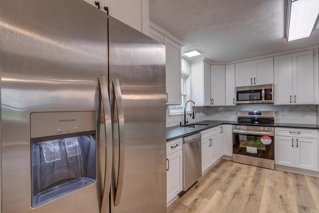 kitchen with white cabinets, stainless steel appliances, light hardwood / wood-style flooring, and sink