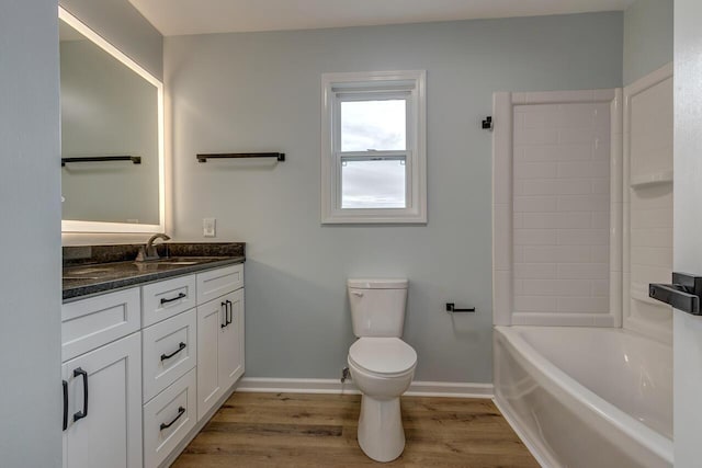 bathroom with a bath, vanity, hardwood / wood-style flooring, and toilet