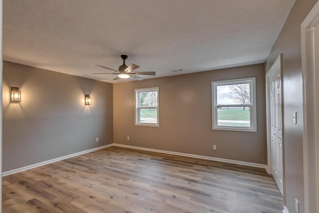 unfurnished room featuring ceiling fan, light wood-type flooring, and a textured ceiling