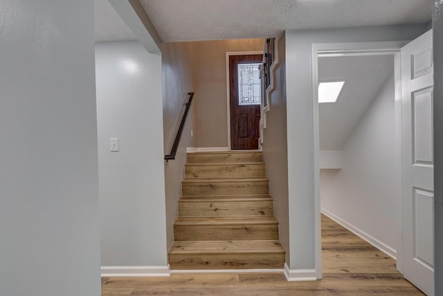 stairway featuring wood-type flooring and a textured ceiling