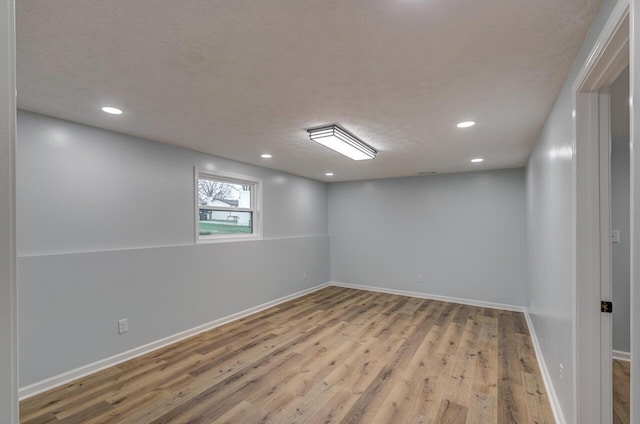 spare room with a textured ceiling and light hardwood / wood-style flooring