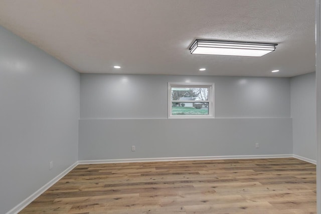 spare room featuring light wood-type flooring and a textured ceiling