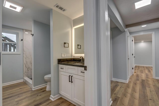 bathroom featuring vanity, toilet, wood-type flooring, and walk in shower