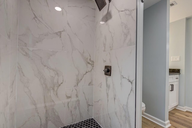 bathroom featuring tiled shower, toilet, vanity, and hardwood / wood-style flooring