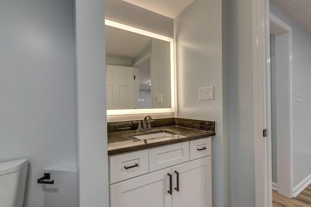 bathroom featuring wood-type flooring, vanity, and toilet