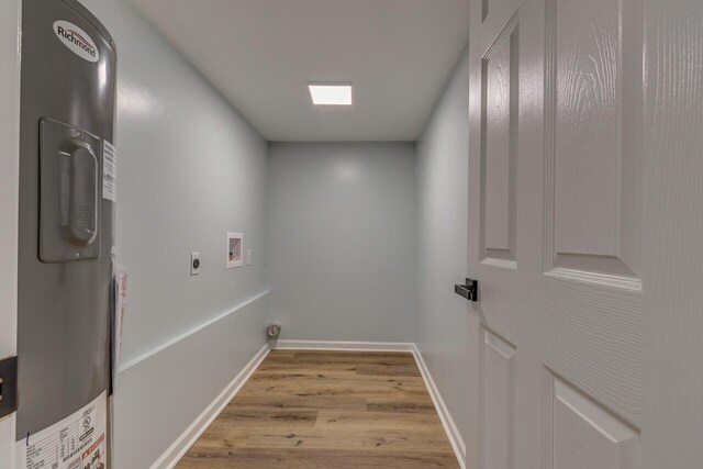 washroom featuring electric water heater, light hardwood / wood-style flooring, washer hookup, and hookup for an electric dryer