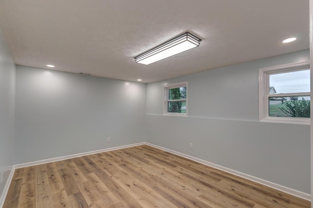 unfurnished room featuring a textured ceiling and light hardwood / wood-style flooring