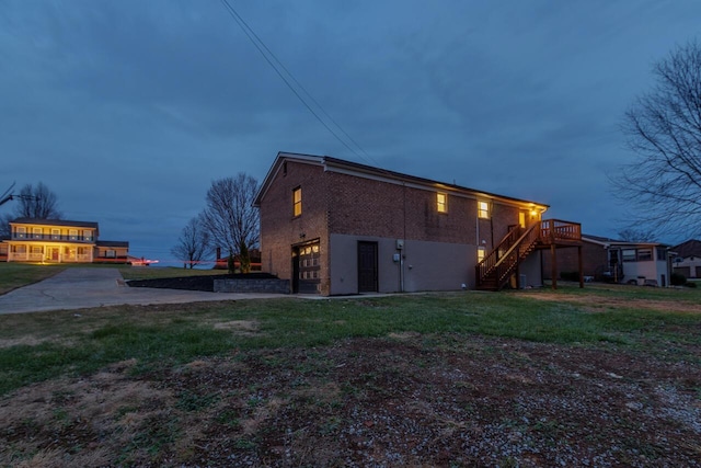 property exterior at dusk featuring a lawn, a garage, and a wooden deck