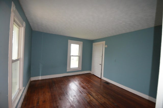 empty room with a textured ceiling and dark wood-type flooring