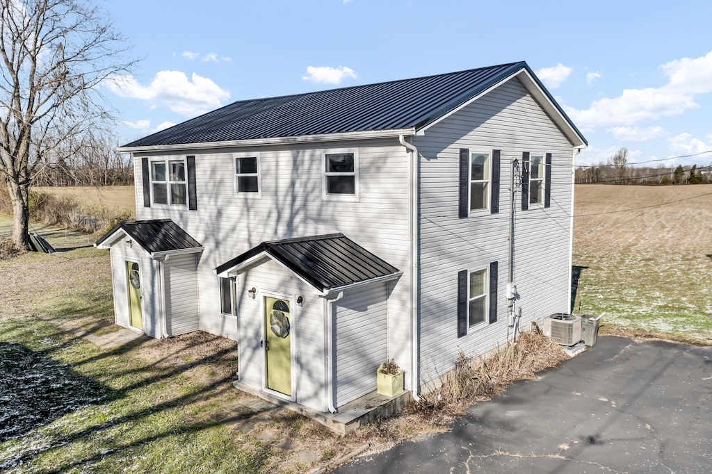 rear view of property featuring a yard and central AC unit