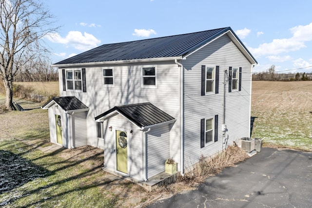 rear view of property featuring a yard and central AC unit