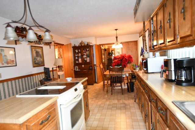 kitchen featuring decorative light fixtures, white appliances, a chandelier, a kitchen island, and sink