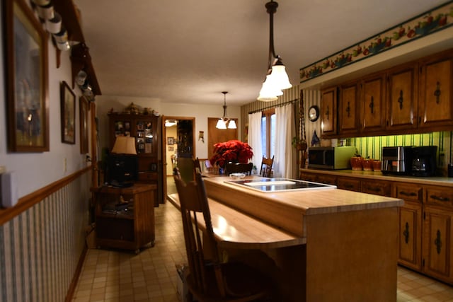 kitchen featuring stovetop, pendant lighting, wooden counters, and a kitchen island