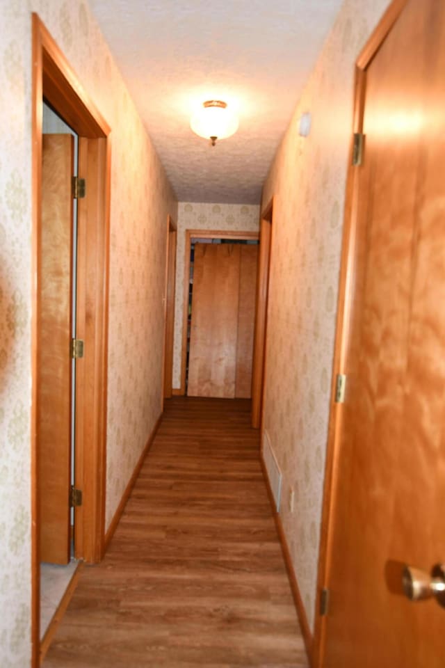 hall featuring light hardwood / wood-style floors and a textured ceiling