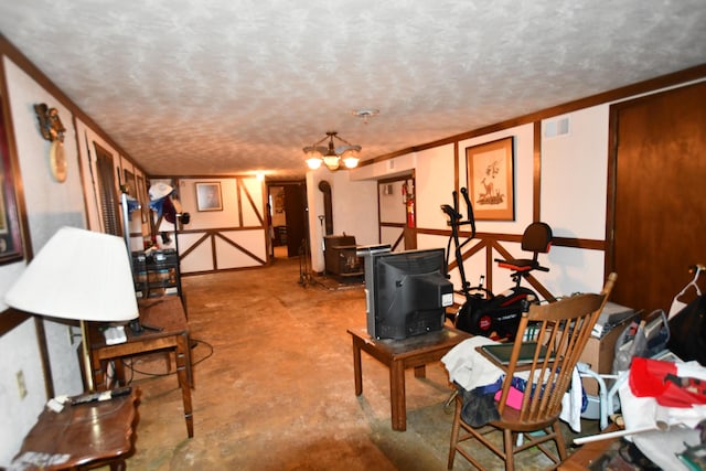 interior space with a wood stove, a textured ceiling, crown molding, and a notable chandelier