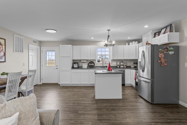 kitchen featuring white cabinets, stainless steel fridge with ice dispenser, decorative light fixtures, and plenty of natural light