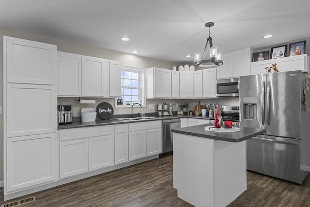 kitchen featuring appliances with stainless steel finishes, dark hardwood / wood-style flooring, sink, white cabinets, and a center island