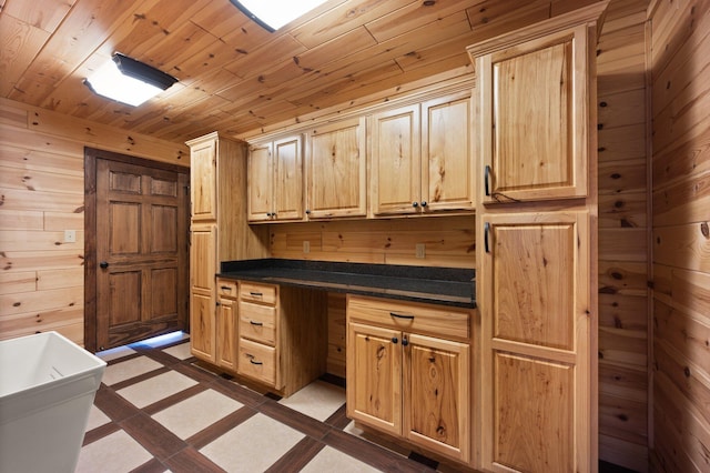 kitchen featuring built in desk, wood ceiling, light brown cabinetry, and wooden walls