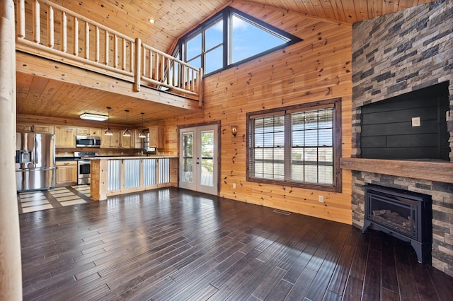 unfurnished living room with high vaulted ceiling, hardwood / wood-style floors, wooden walls, a fireplace, and wood ceiling