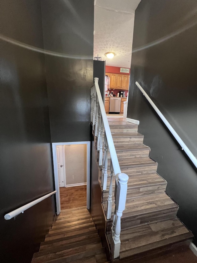 stairs with a textured ceiling and hardwood / wood-style flooring