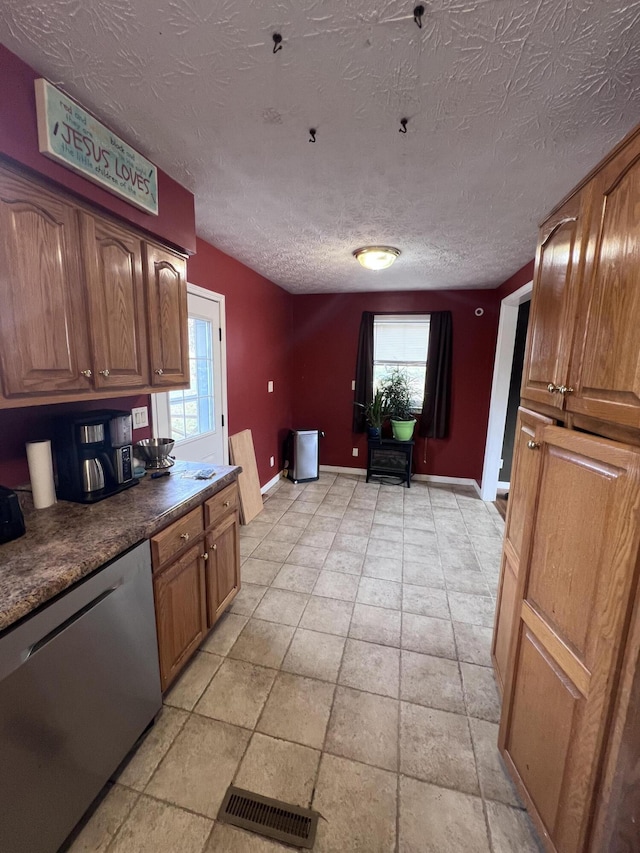 kitchen featuring a textured ceiling, stainless steel dishwasher, and a healthy amount of sunlight