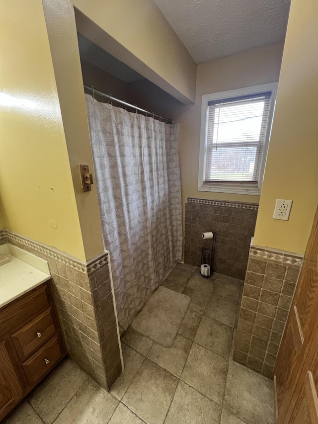 bathroom featuring vanity and tile walls