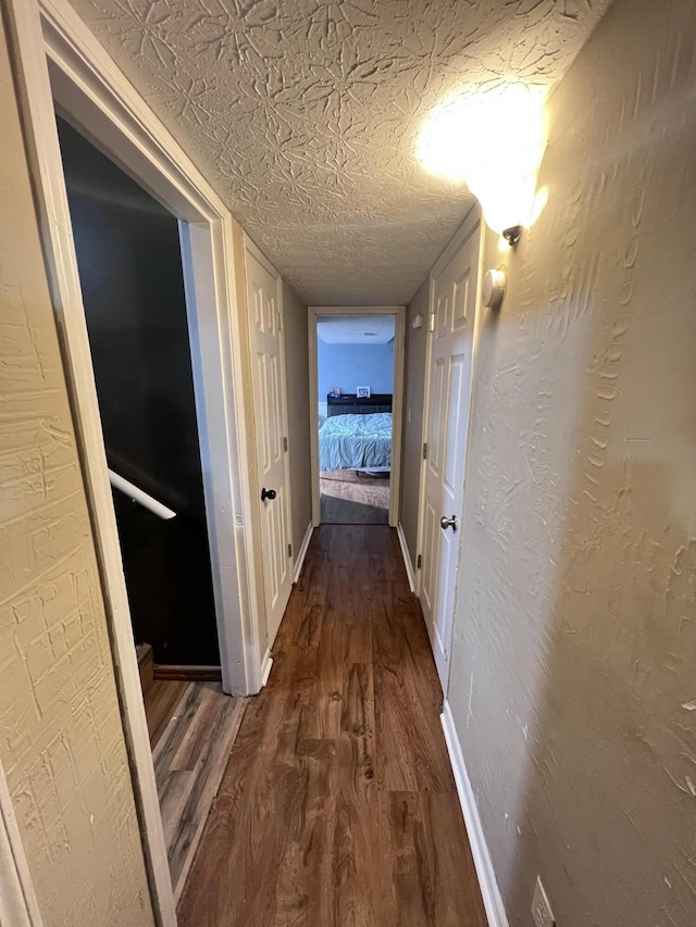 corridor with dark wood-type flooring and a textured ceiling