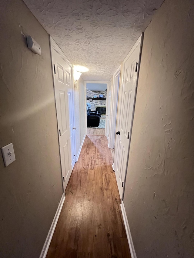 hallway with light hardwood / wood-style flooring and a textured ceiling