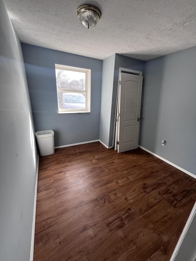 spare room with a textured ceiling and dark hardwood / wood-style floors