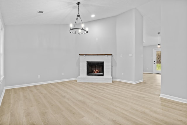 unfurnished living room featuring a fireplace, light hardwood / wood-style floors, and a chandelier