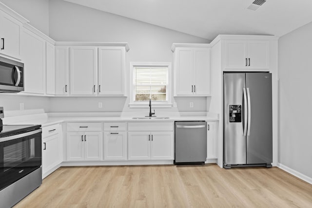 kitchen featuring white cabinetry, sink, appliances with stainless steel finishes, and vaulted ceiling