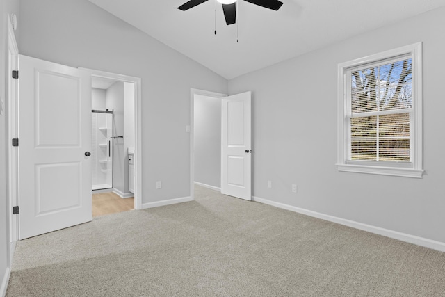 unfurnished bedroom featuring ensuite bath, ceiling fan, light carpet, and lofted ceiling