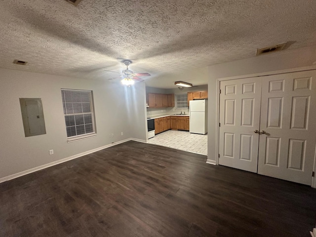 unfurnished living room with dark hardwood / wood-style flooring, a textured ceiling, electric panel, and ceiling fan