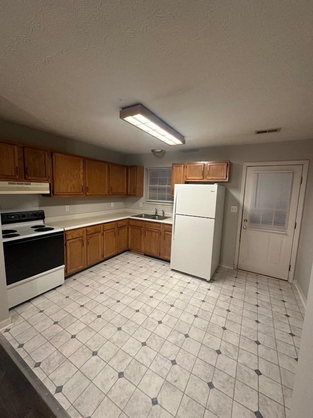 kitchen with a textured ceiling, sink, and white appliances