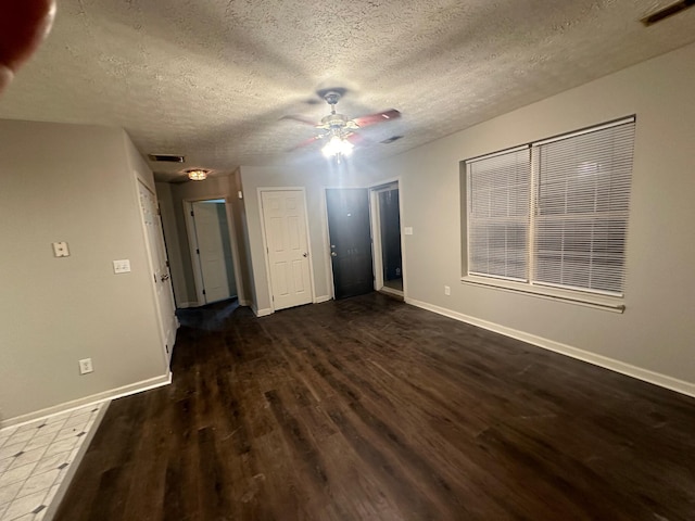 unfurnished bedroom featuring ceiling fan, dark wood-type flooring, and a textured ceiling