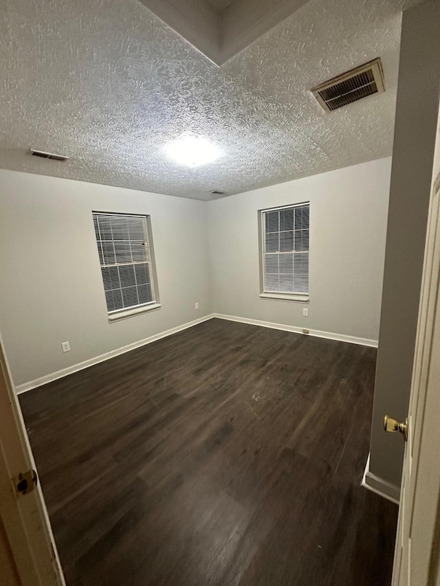 spare room with dark wood-type flooring and a textured ceiling