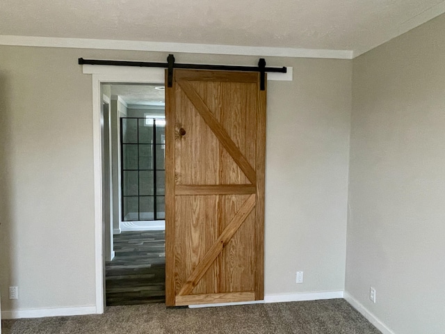 carpeted spare room featuring ornamental molding and a barn door