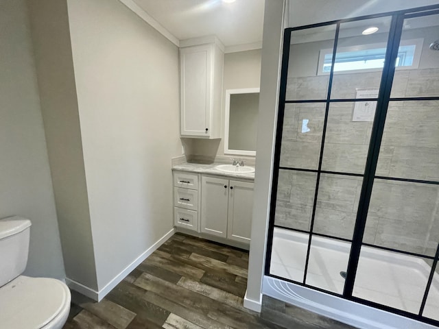 bathroom with wood-type flooring, toilet, vanity, and a shower with shower door