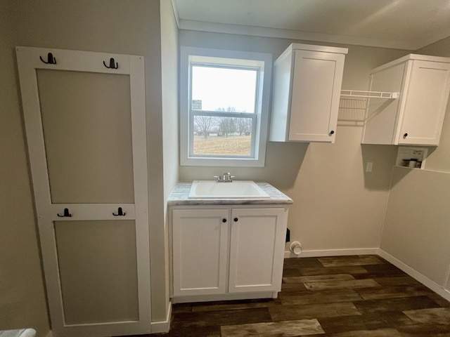 laundry area with dark wood-type flooring, sink, cabinets, ornamental molding, and hookup for a washing machine