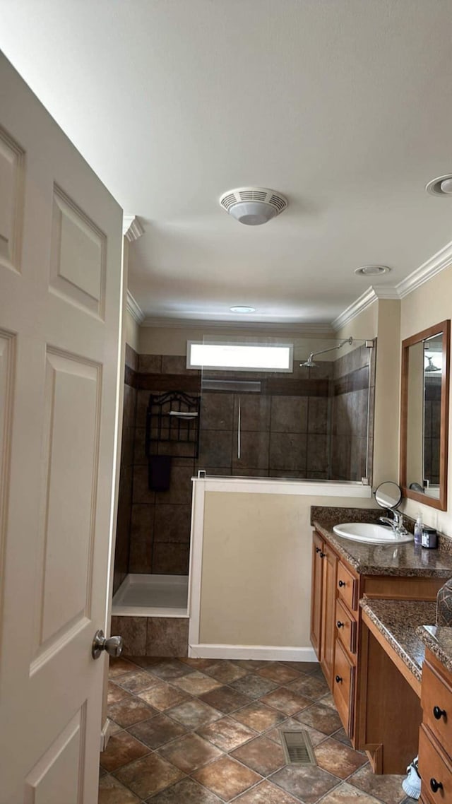 bathroom with ornamental molding, tiled shower, and vanity