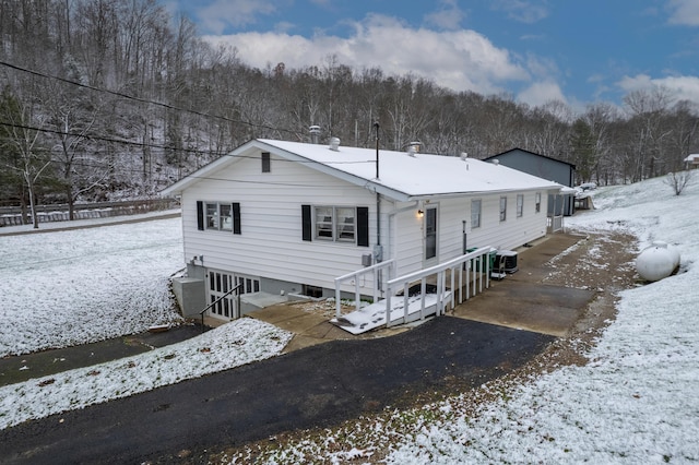 snow covered house featuring cooling unit