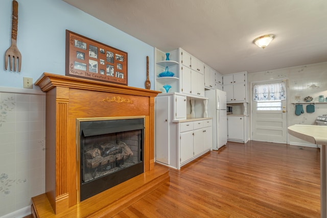 interior space with white cabinets, light hardwood / wood-style flooring, white fridge, and tile walls