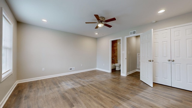 unfurnished bedroom with ceiling fan, wood-type flooring, and connected bathroom