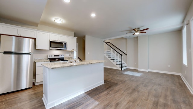 kitchen featuring dark wood-type flooring, white cabinets, an island with sink, and appliances with stainless steel finishes