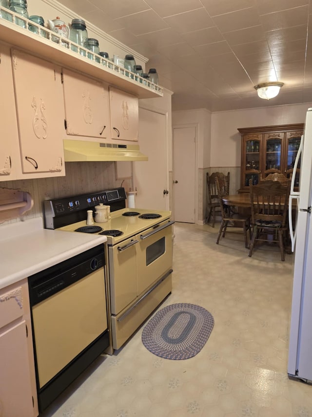 kitchen with white cabinetry, wood walls, and white appliances