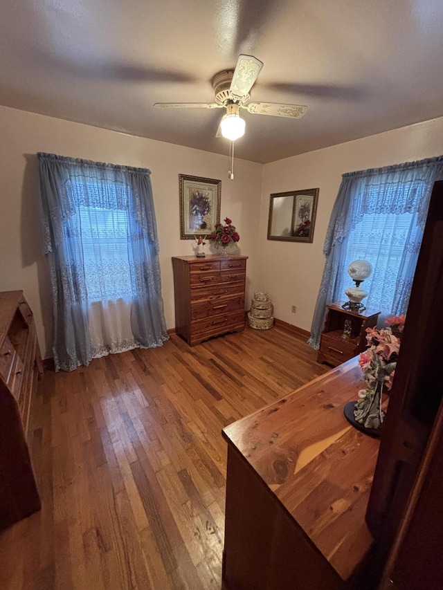 bedroom with multiple windows, ceiling fan, and wood-type flooring